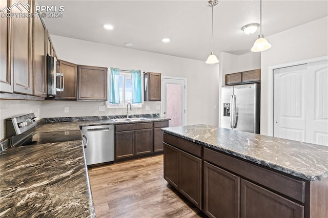 kitchen featuring sink, hanging light fixtures, light hardwood / wood-style floors, appliances with stainless steel finishes, and a kitchen island