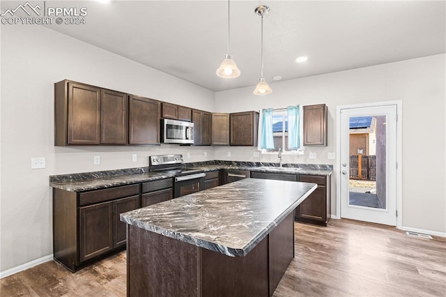 kitchen featuring dark brown cabinetry, sink, a center island, decorative light fixtures, and appliances with stainless steel finishes