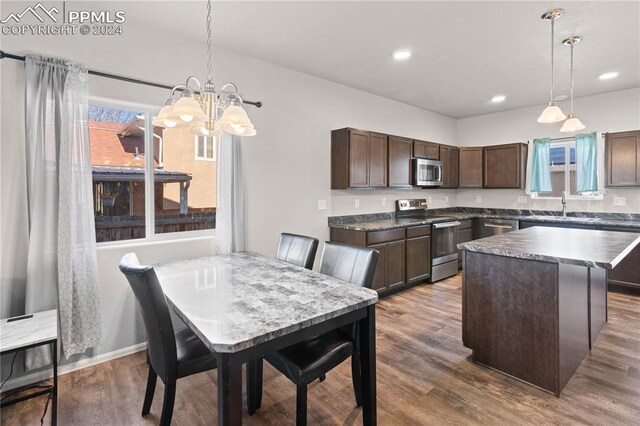 kitchen featuring appliances with stainless steel finishes, a center island, dark hardwood / wood-style flooring, and pendant lighting