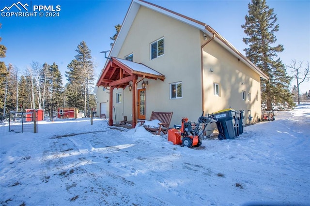 snow covered back of property featuring a garage