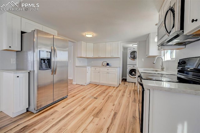 kitchen featuring white cabinetry, sink, stacked washer / drying machine, stainless steel appliances, and light hardwood / wood-style flooring