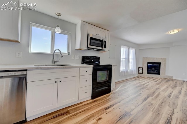 kitchen with sink, white cabinetry, light hardwood / wood-style flooring, pendant lighting, and stainless steel appliances