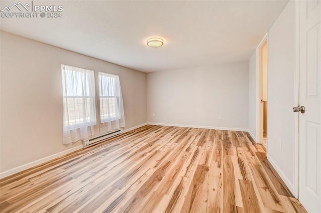 unfurnished bedroom with baseboard heating and light hardwood / wood-style flooring