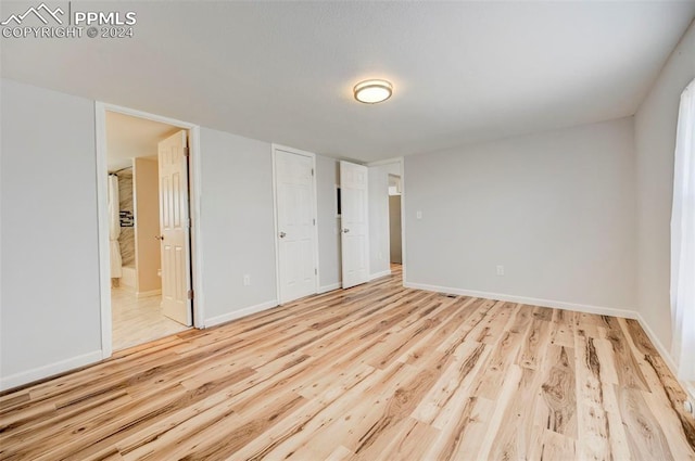 unfurnished bedroom featuring ensuite bathroom and light hardwood / wood-style floors