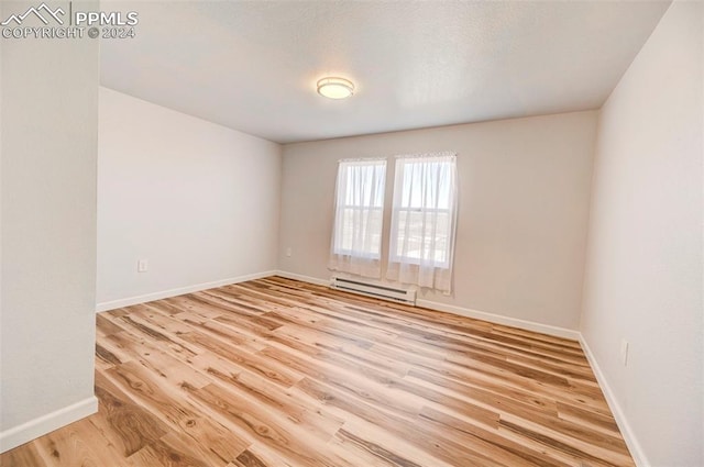 empty room featuring baseboard heating and light wood-type flooring