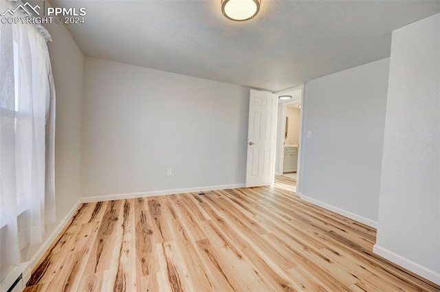 empty room with baseboard heating and light wood-type flooring