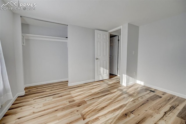 unfurnished bedroom with light wood-type flooring and a closet