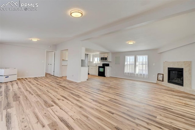 unfurnished living room featuring beam ceiling, a high end fireplace, and light hardwood / wood-style floors