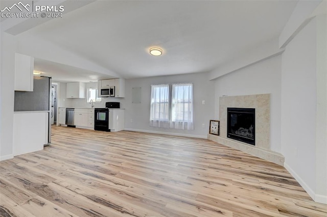 unfurnished living room with sink, a high end fireplace, and light hardwood / wood-style flooring