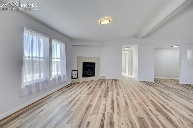 unfurnished living room featuring beamed ceiling and light hardwood / wood-style flooring