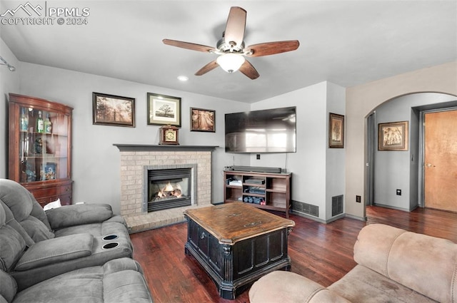 living room featuring ceiling fan, dark hardwood / wood-style floors, and a brick fireplace