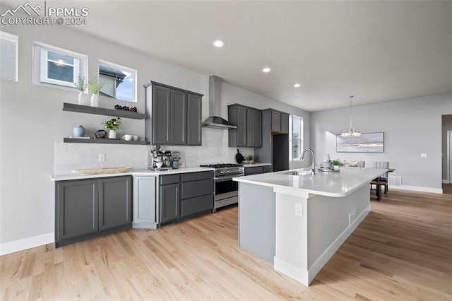 kitchen with wall chimney exhaust hood, sink, stainless steel stove, and light hardwood / wood-style floors