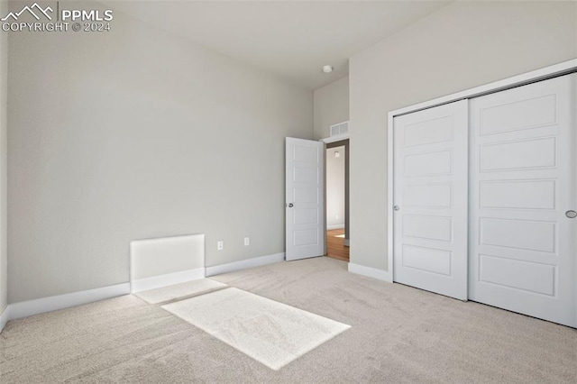 unfurnished bedroom with light carpet and a closet