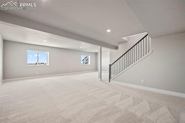 basement with a healthy amount of sunlight and light colored carpet