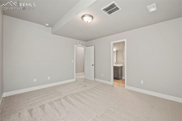 unfurnished bedroom with light colored carpet and ensuite bath