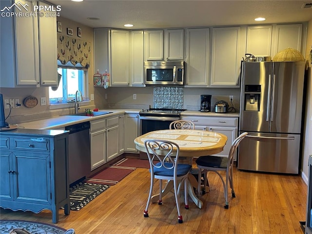 kitchen featuring white cabinets, appliances with stainless steel finishes, light wood-type flooring, and sink