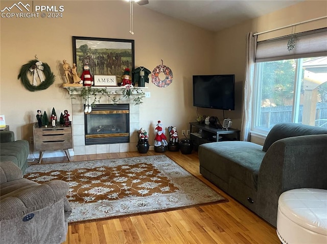 living room featuring a tiled fireplace and wood-type flooring