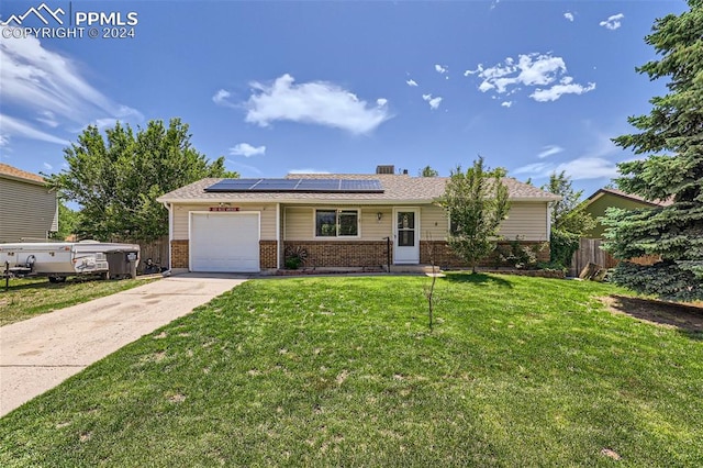 single story home with a garage, a front yard, and solar panels