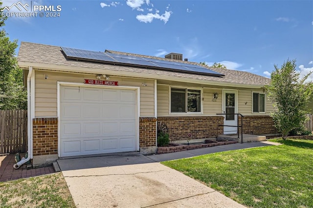 single story home featuring solar panels, a garage, and a front lawn