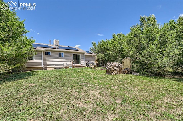 rear view of property featuring a lawn and solar panels