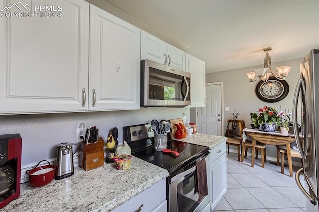 kitchen featuring white cabinets, light stone counters, a chandelier, light tile patterned flooring, and appliances with stainless steel finishes