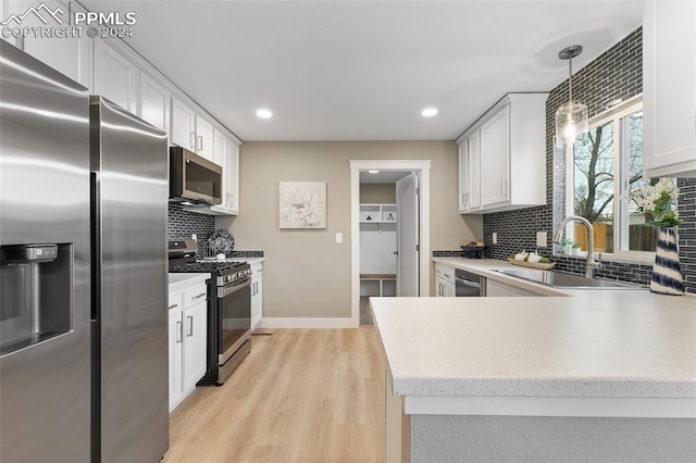 kitchen with backsplash, sink, hanging light fixtures, white cabinetry, and stainless steel appliances