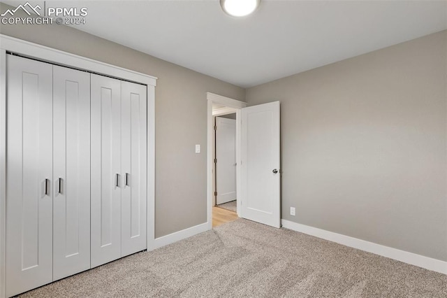 unfurnished bedroom with light carpet and a closet