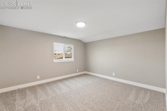 carpeted spare room featuring vaulted ceiling