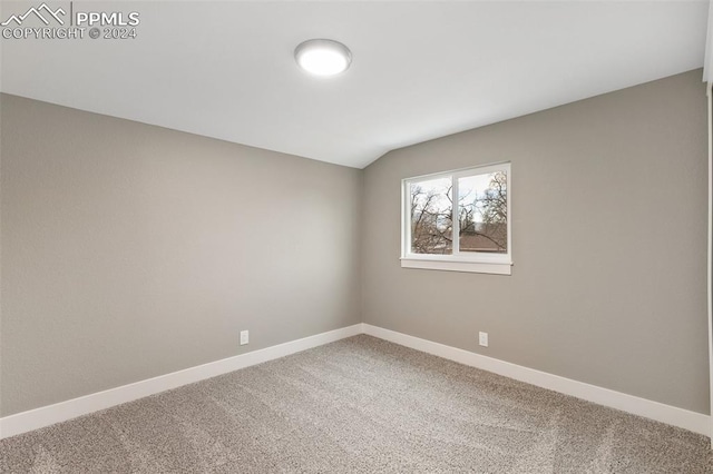 carpeted empty room with vaulted ceiling