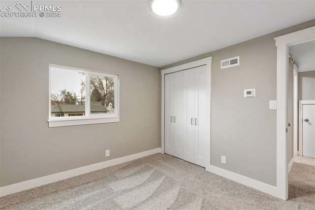 unfurnished bedroom with a closet, carpet, and vaulted ceiling