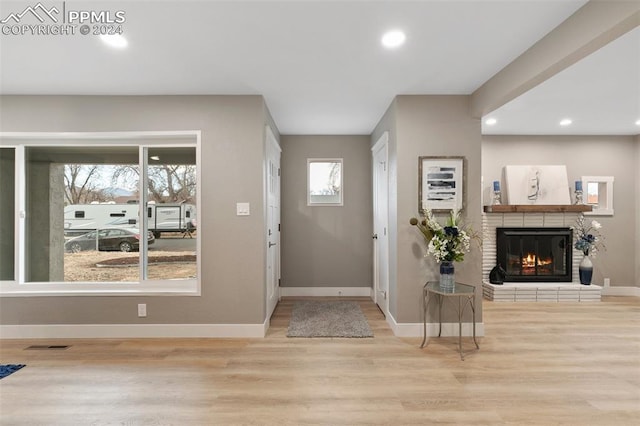 entrance foyer featuring light hardwood / wood-style floors and a brick fireplace