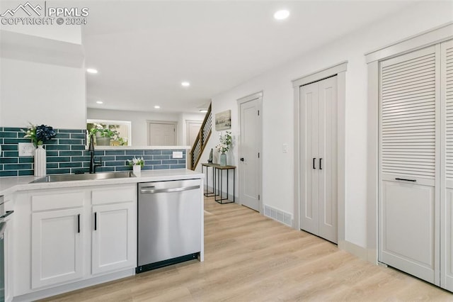 kitchen featuring backsplash, stainless steel dishwasher, sink, light hardwood / wood-style flooring, and white cabinetry