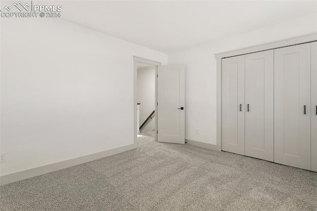 unfurnished bedroom featuring light carpet and a closet