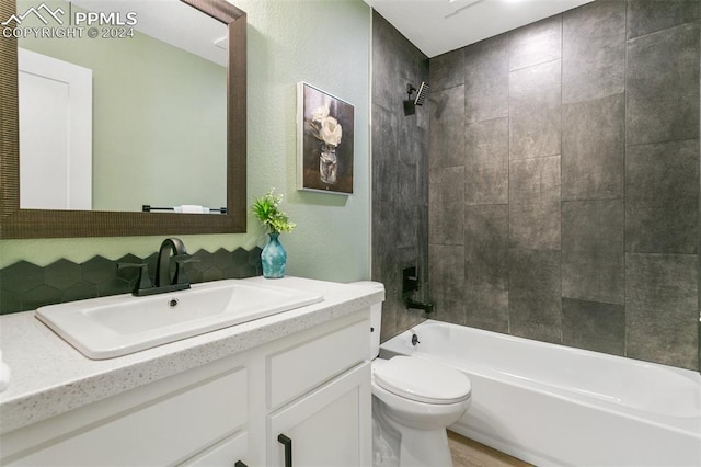 full bathroom featuring vanity, tiled shower / bath combo, and toilet