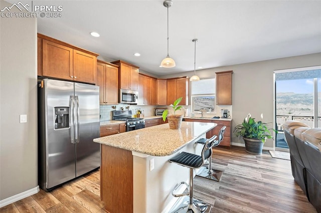 kitchen featuring appliances with stainless steel finishes, decorative light fixtures, a center island, plenty of natural light, and a breakfast bar area