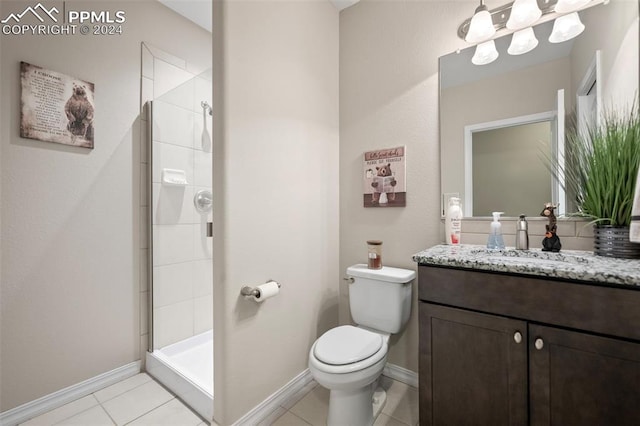 bathroom with vanity, toilet, tile patterned flooring, and tiled shower