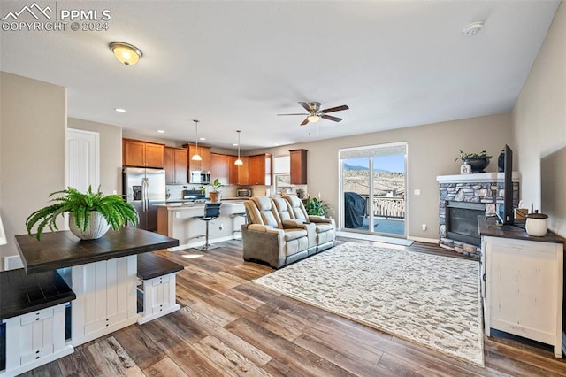 living room featuring ceiling fan, a fireplace, and hardwood / wood-style floors