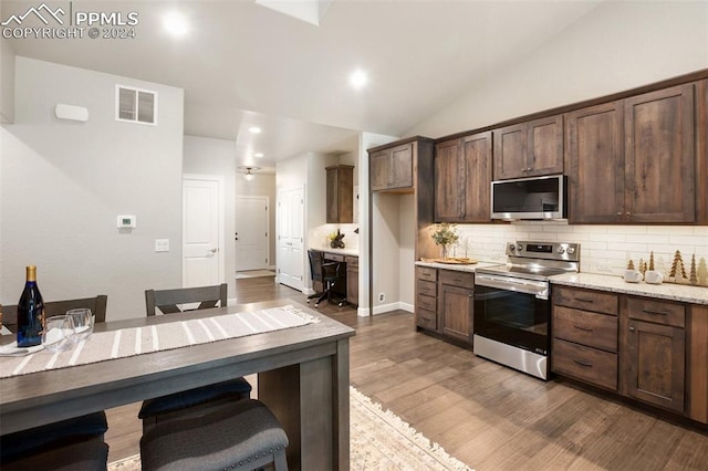 kitchen with backsplash, dark wood-type flooring, light stone countertops, dark brown cabinetry, and stainless steel appliances