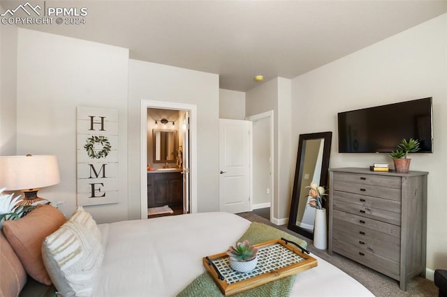 bedroom with ensuite bathroom and carpet floors