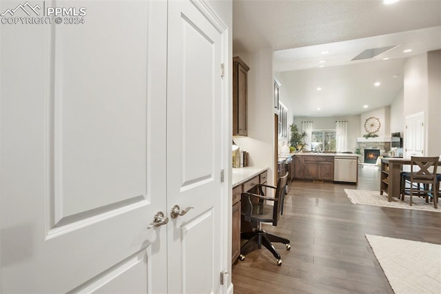 interior space with dark hardwood / wood-style flooring, dishwasher, and a stone fireplace