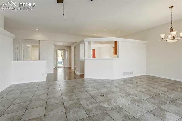 unfurnished living room featuring tile patterned flooring and ceiling fan with notable chandelier