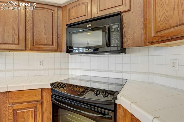 kitchen featuring backsplash, tile countertops, and black appliances