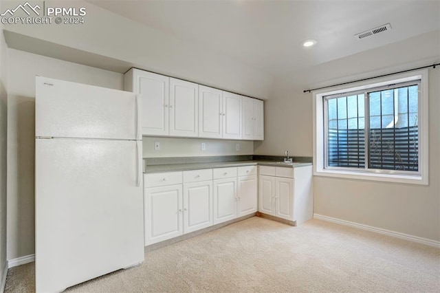 kitchen with white cabinetry, sink, white fridge, and light carpet