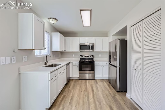 kitchen featuring sink, white cabinets, light hardwood / wood-style floors, and appliances with stainless steel finishes