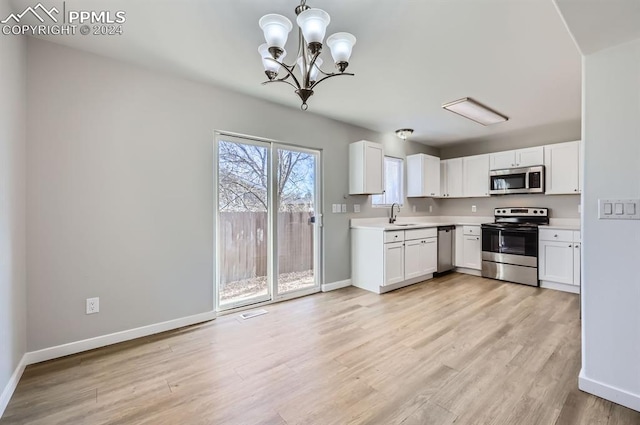 kitchen with an inviting chandelier, white cabinets, sink, appliances with stainless steel finishes, and light hardwood / wood-style floors