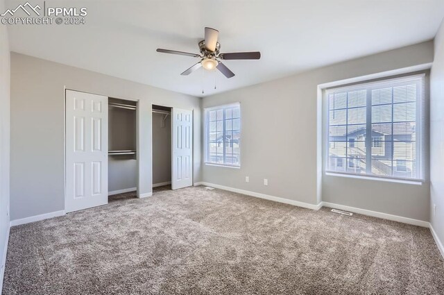 unfurnished bedroom with multiple closets, ceiling fan, and carpet floors