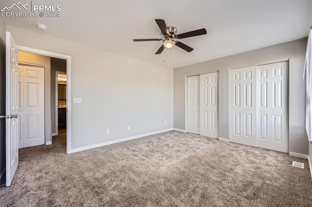 unfurnished bedroom with carpet flooring, ceiling fan, and multiple closets