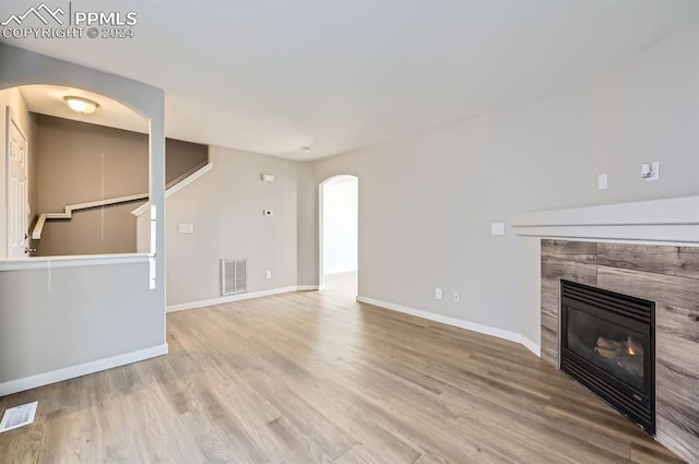 unfurnished living room with a tile fireplace and light hardwood / wood-style flooring