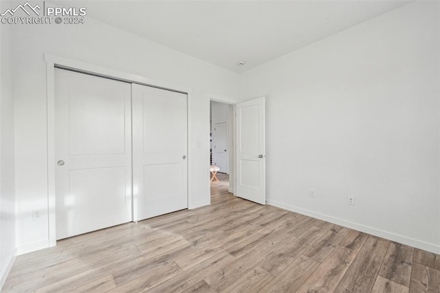 unfurnished bedroom with a closet and light hardwood / wood-style floors