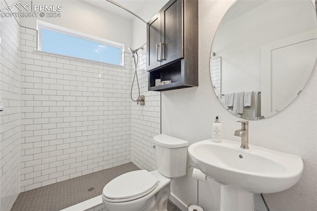 bathroom featuring tiled shower, toilet, and sink